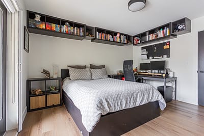 A well-organized bedroom with light wood laminate flooring and white walls.