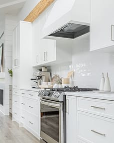 A modern kitchen with white cabinets, a white subway tile backsplash, and stainless steel appliances by kitchen renovation contractor in Langley