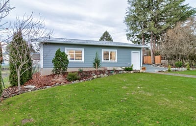 A detached, single-story building with a gray exterior, multiple windows, and a white door by home renovation contractors in Langley, BC