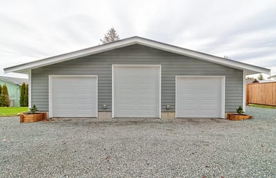 A large, detached outbuilding garage with three car bays and a gravel driveway made by by Bowline Construction in Langley, BC