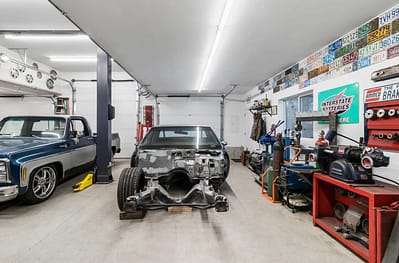 A large, well-lit outbuilding garage with a car lift and multiple vintage cars by Bowline Construction in Langley, BC