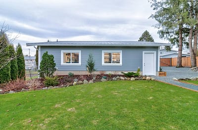 A detached, single-story building with a gray exterior, multiple windows, and a white door by home renovation contractors in Langley, BC