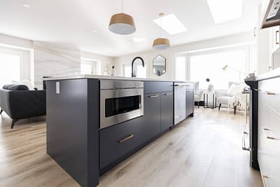 Contemporary kitchen featuring a gray island with a white countertop, pendant lights, and stainless steel appliances in Langley, BC