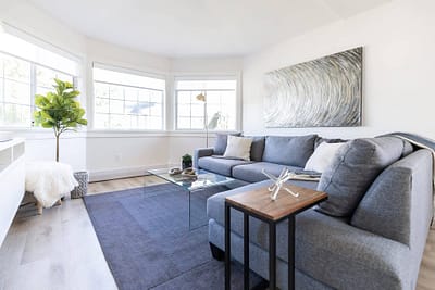 Contemporary living room with a large gray sectional sofa, a glass coffee table, and a large abstract painting in Langley, BC