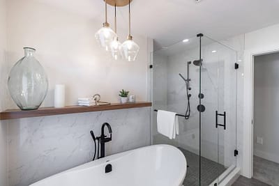 bathroom featuring a freestanding tub, a glass shower, and pendant lights by custom home builder langley, BC