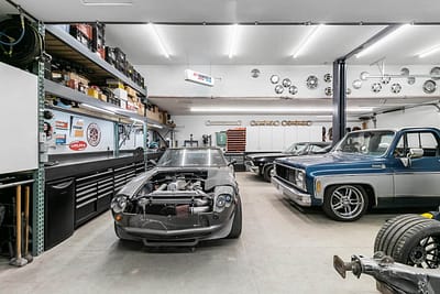 A well-equipped outbuilding garage with a classic car, shelves full of tools and supplies, and a workbench by Bowline Construction in Langley, BC