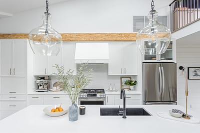 A modern kitchen with white cabinets, a white quartz countertop, a black farmhouse sink, and a black faucet by kitchen renovation contractor in Langley