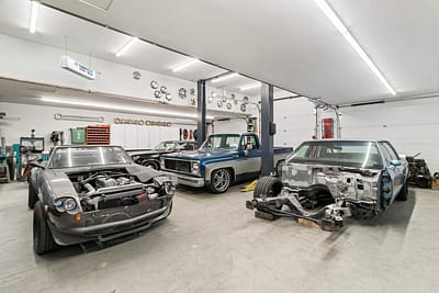 A large, well-lit outbuilding garage with a car lift and multiple vintage cars by Bowline Construction in Langley, BC