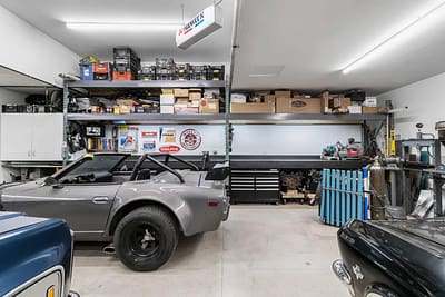 A well-equipped outbuilding garage with a classic car, shelves full of tools and supplies, and a workbench by Bowline Construction in Langley, BC