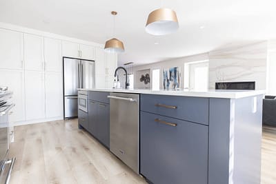 Contemporary kitchen featuring a gray island with a white countertop, pendant lights, and stainless steel appliances in Langley, BC