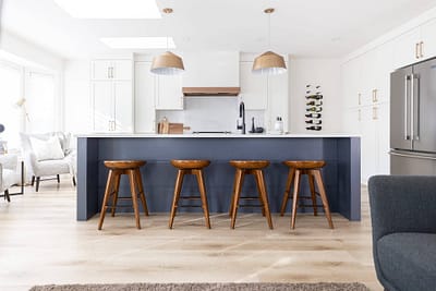 Kitchen island with four stools, pendant lights, and white cabinets by kitchen renovation contractor in Langley