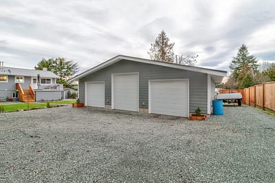 A large, detached outbuilding garage with three car bays and a gravel driveway made by by Bowline Construction in Langley, BC