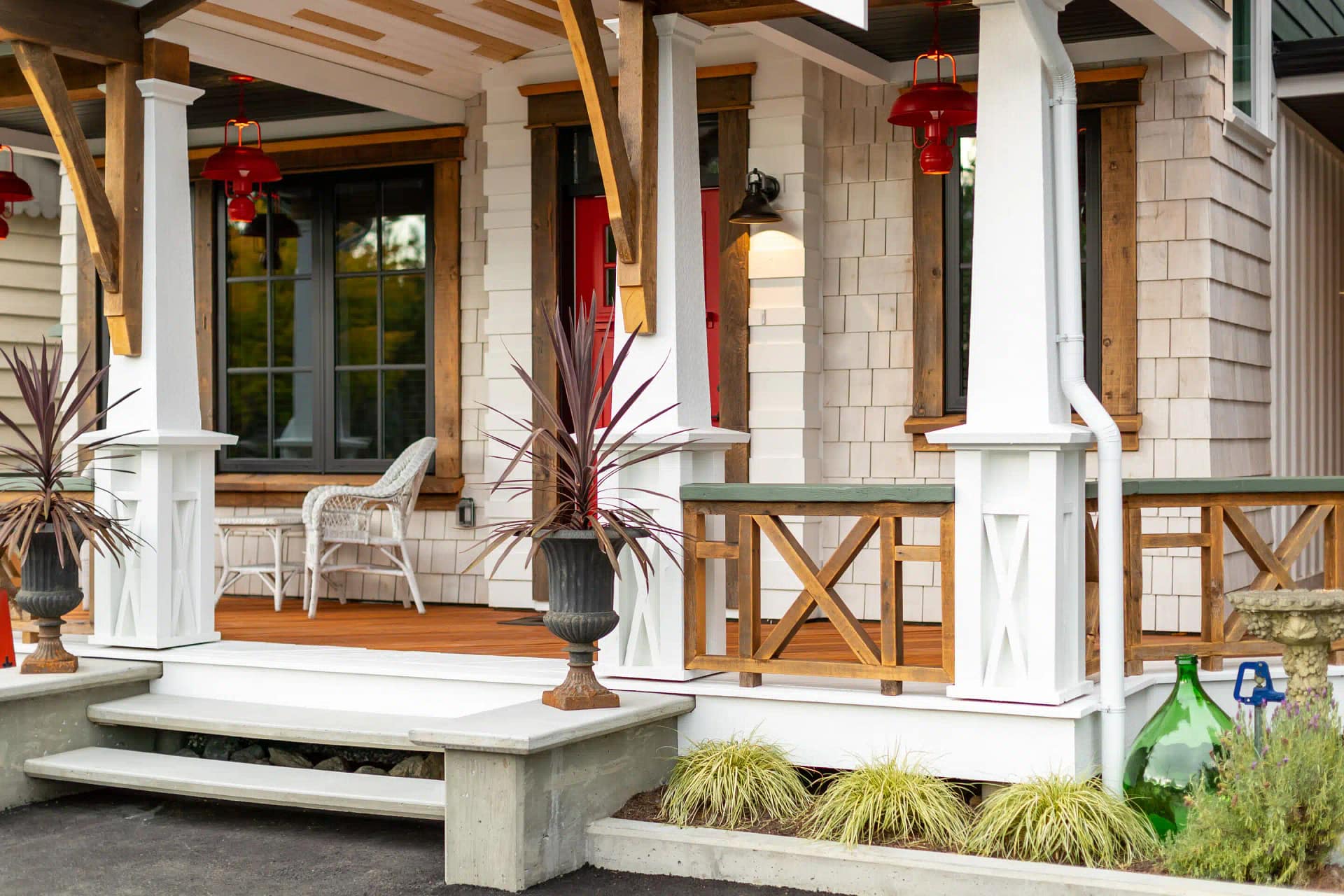 Charming front porch with a red door, white columns, and potted plants by home renovation contractors in Langley.