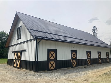 A barn with black roof and white sidings by pole barn construction company in langley