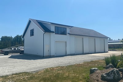 A white pole barn standing tall against the clear sky, a testament to expert pole barn construction in Langley, BC