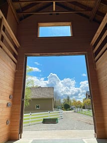 A large, open barn with a view of a clear blue sky and a green field in Langley, BC