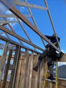 A pole barn construction worker on a wooden roof in Langley, BC