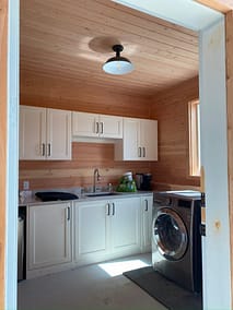 A bright and airy laundry room with white cabinets, a sink, and a washer and dryer by home renovation contractors in Langley, BC