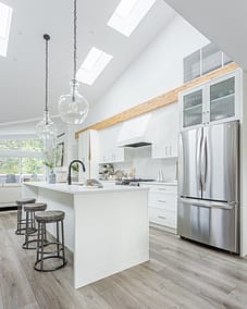 A bright, modern kitchen with white cabinets and a large white countertop island.