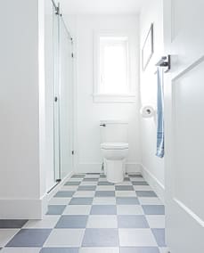 An image of a bathroom with black and white tiles with toilet and shower that is made by home renovation contractors in Langley, BC