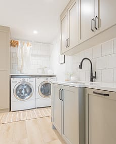 A picture of a laundry area with washing machines, cabinet and a sink made by a custom home builder langley in Langley, BC