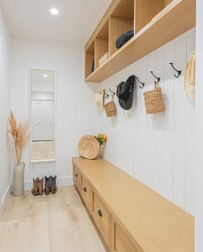 A hallway with custom designed wooden shelves and hats on hook with custom additions in Langley, BC