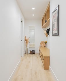 A hallway with custom designed wooden shelves and hats on hook with custom additions in Langley, BC