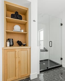 An image of a bathroom with black tiles and custom additions wooden cabinet in Langley, BC