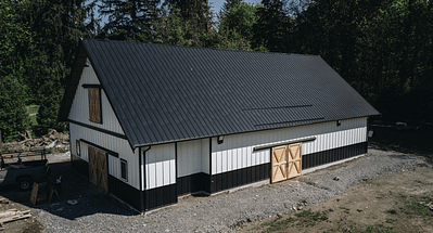 A barn with black roof and white sidings by pole barn construction company in langley