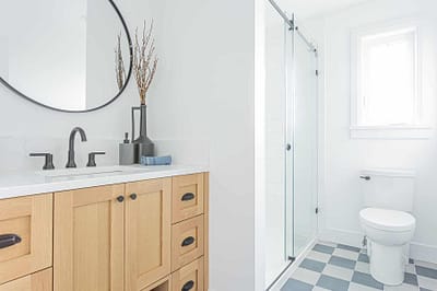 An image of a bathroom faucet with wooden countertop and a toilet bowl made by a home renovation contractors in Langley, BC