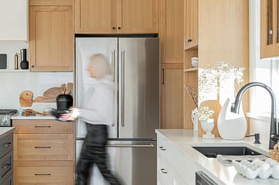A picture of a kitchen with wooden accent and a person walking made by kitchen renovation contractor in Langley, BC