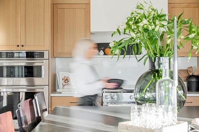 A picture of a kitchen with wooden accent and a person walking made by kitchen renovation contractor in Langley, BC
