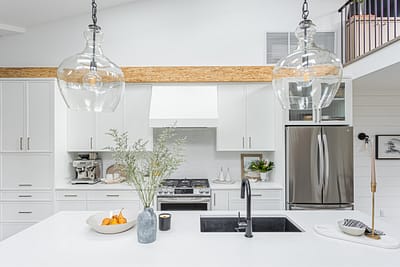 A bright, modern kitchen with white cabinets and a large white countertop island.