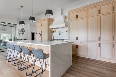 Spacious kitchen with light wood cabinets, a large island, and pendant lights by home renovation contractors in Langley.