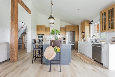 A bright, modern kitchen with a large island featuring a gray base and a stainless steel countertop.
