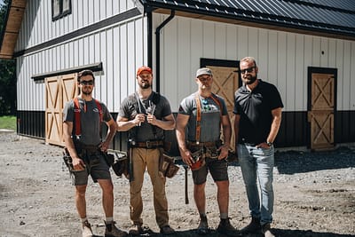Bowline Construction pole barn construction team members behind a pole barn with a black roof and white siding in Langley, BC