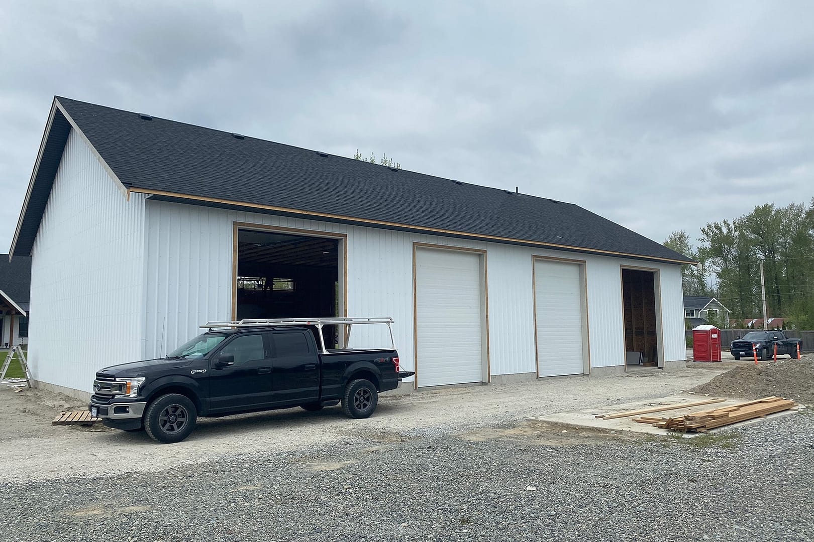 A white pole barn with a black roof, a testament to expert pole barn construction in Langley, BC