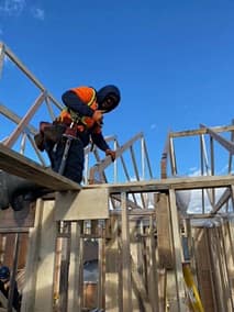 A enovation contractor on top of a wooden plank in a process of pole barn construction in Langley, BC
