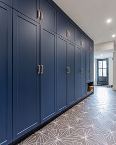 A long hallway featuring a wall of dark blue built-in cabinets with gold handles.
