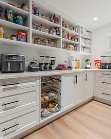 A custom-built pantry in Langley with white shaker-style cabinets, open shelving filled with various food items