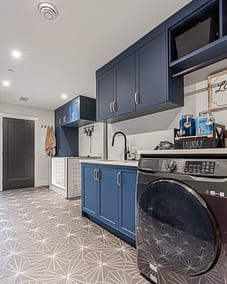 A well-organized laundry room with dark blue cabinets and gold handles.
