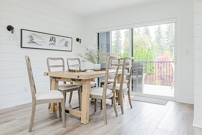 A white accent dining area with wooden tables and floors by renovation company in Langley, BC