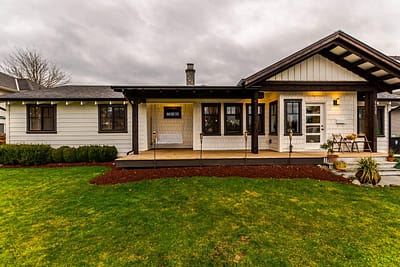 A one-story house with a covered porch, a swing, and a grassy yard