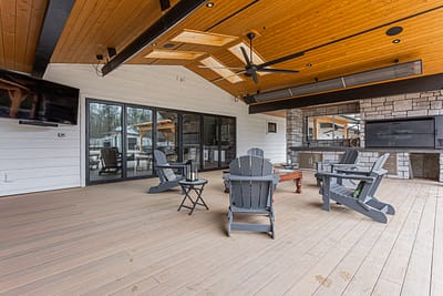 An outdoor covered patio with wood ceiling, stone fireplace, and Leisure Line Recycled Plastic Folding Adirondack Chairs.