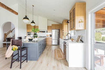 A bright, modern kitchen with a large island featuring a gray base and a stainless steel countertop.