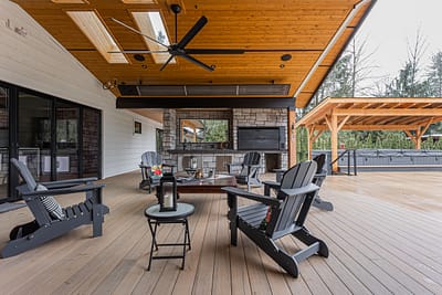 An outdoor covered patio with wood ceiling, stone fireplace, and Leisure Line Recycled Plastic Folding Adirondack Chairs.