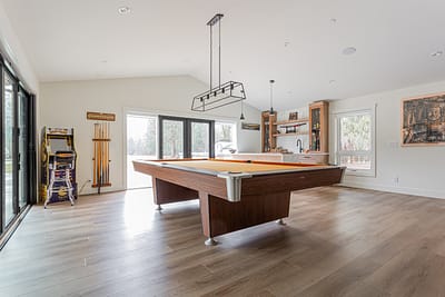 A room with custom additon wooden shelves, a cabinet, and a partial view of a pool table