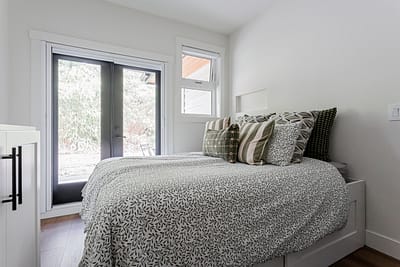 A bright, modern bedroom with white walls and light wood laminate flooring by a renovation company in Langley, BC