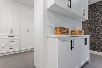 White shaker cabinets in Langley with "Top Knobs Hopewell Bar Pulls" and wooden boxes on the counter.