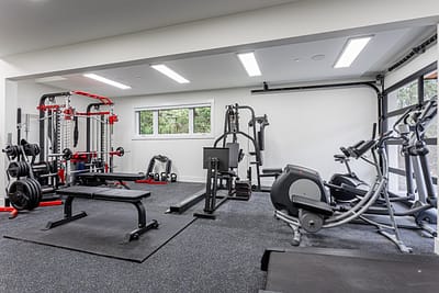 A well-equipped custom addition home gym with gray rubber flooring in Langley, BC